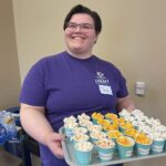 Photo of library staff person holding a serving tray of popcorn samples at memory café.