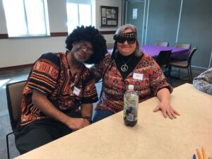 Two older people sitting at a table dressed up in 60s costumes