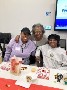 Three women of color posing together while sitting and playing bingo