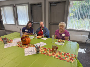Three women smile for the camera as they eat a light lunch.
