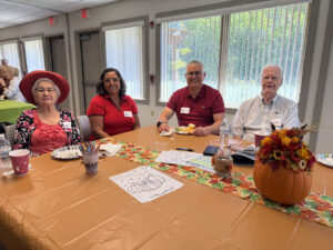 A group of people smile for the camera at a Fall-themed Memory Cafe.