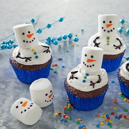 Chocolate cupcakes decorated to resemble snowmen with white frosting and a marshmallow head.