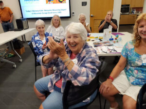 A group of older adults smile and clap at a memory cafe event.