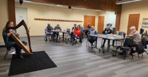 A harpist performs for a group of older adults.