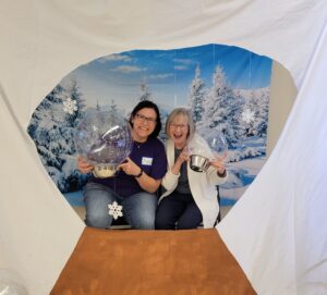 Two Memory Cafe organizers pose with giant snow globes