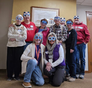 A group shot of Memory Cafe participants all wearing fun snow day-themed glasses.