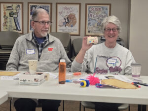 A woman shows off the treasure box she decorated next to a man with the name tag Dick