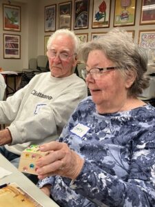 A woman in a floral shirt holds a treasure box she decorated with plastic gems.