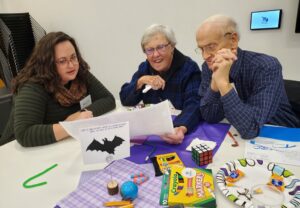 A woman shows a something on a sheet of paper to two other people.