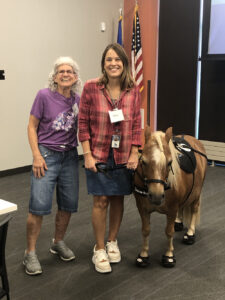 A Memory Cafe organizer poses with the trainer for a miniature horse.