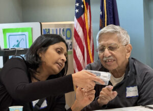 A woman shows a man the label of a small plastic container.