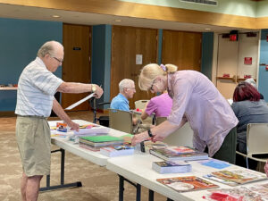 A man and woman look at magazines they want to use for a collage craft.