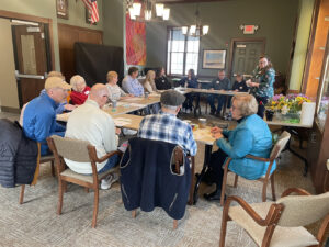 Participants at a Memory Cafe sit a at a table before learning flower arranging.