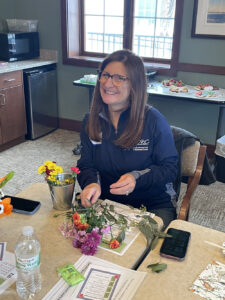 A Memory Cafe worker makes a flower arrangement in a little silver bucket