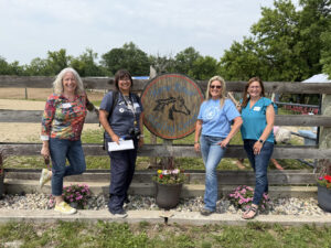 Four women post in front of a sign that reads "Horse Power Healing Center"