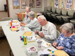 A line of Memory Cafe participants focus on an activity sheet in front of them.