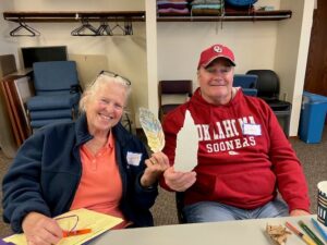 A woman and a man show off the paper feathers they decorated at a Memory Cafe.