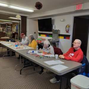 Four people sit at a table doing activities
