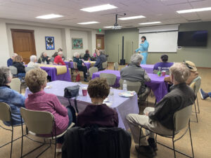 An Elvis impersonator stands in front of a group of Memory Cafe participants.