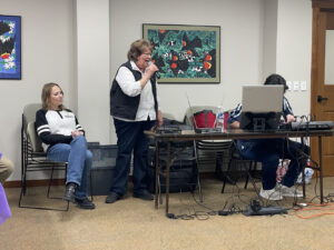A woman speaks into a microphone at an event for the Library Memory Project.