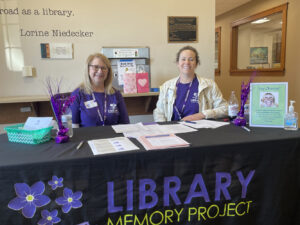 Two workers for the Library Memory Project man a table at an event.