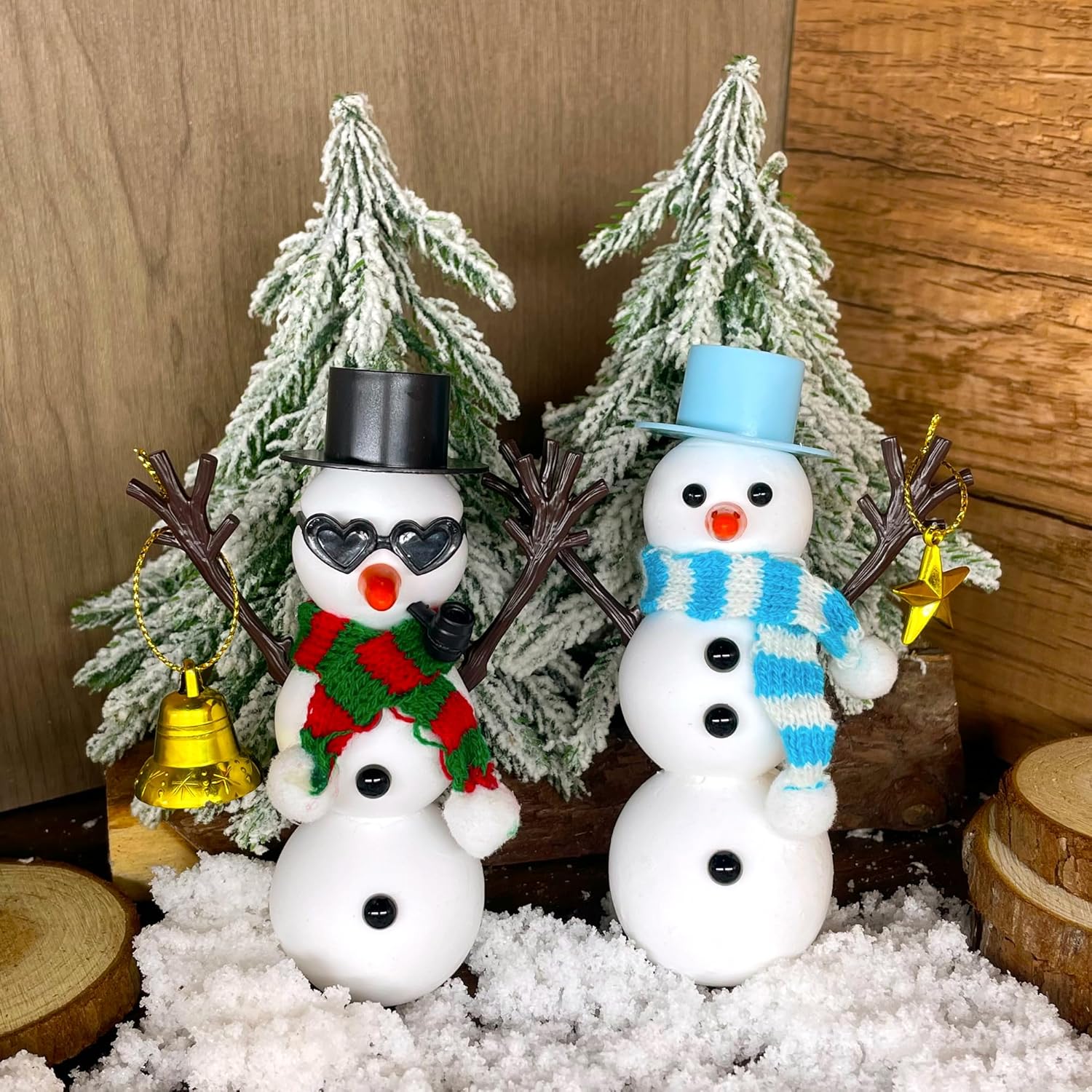 Two craft snowmen standing side by side in front of fake pine trees