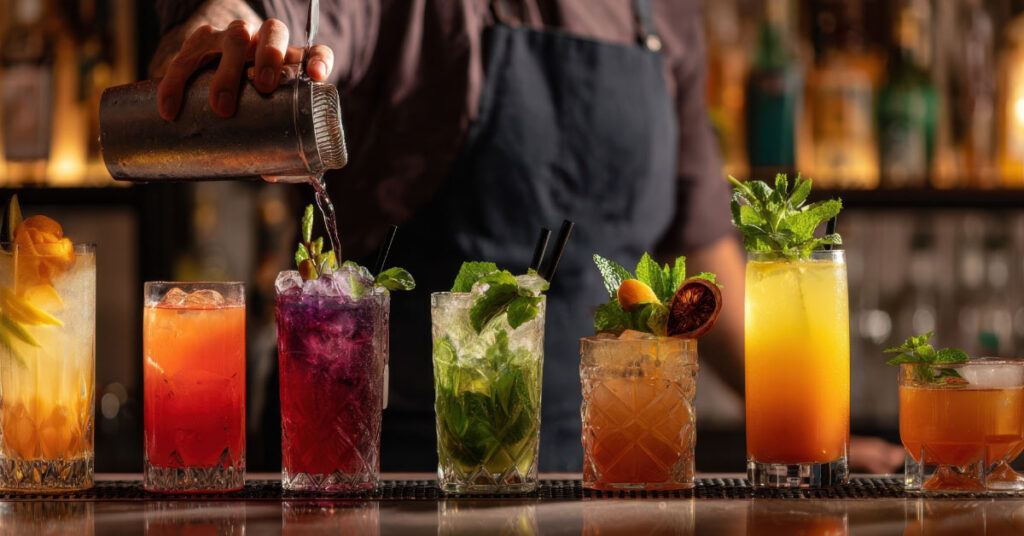 A line of colorful tropical mocktails on a bar.