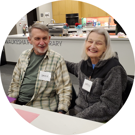 An older couple sitting behind a table smiling