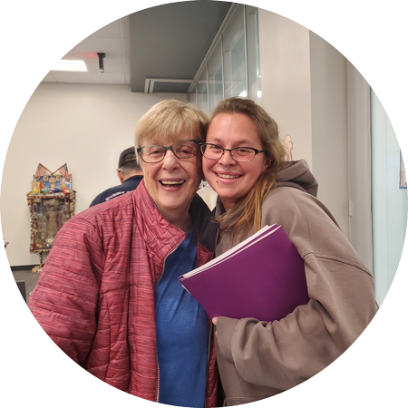 An older woman and a younger woman posing close together smiling big