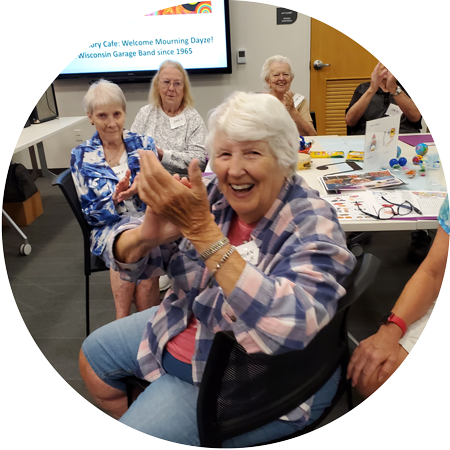 Elderly women sitting at a table in a meeting room clapping