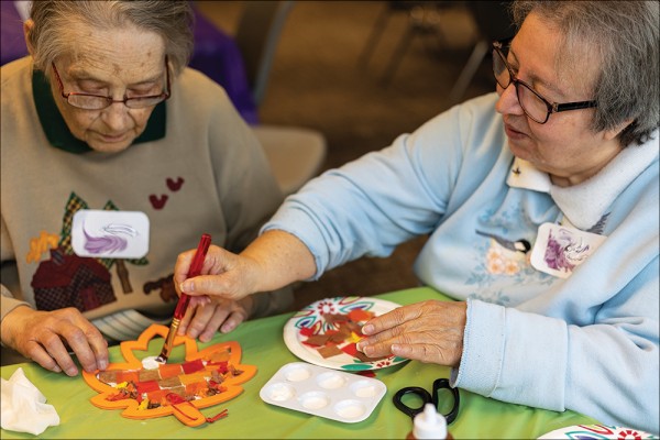 Two elderly women working on a craft project together