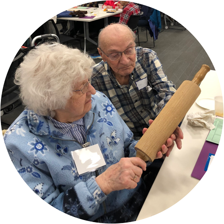 An elderly couple examine a wooden rolling pin