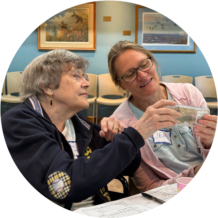 A middle-aged woman and an elderly woman looking at something they are holding together