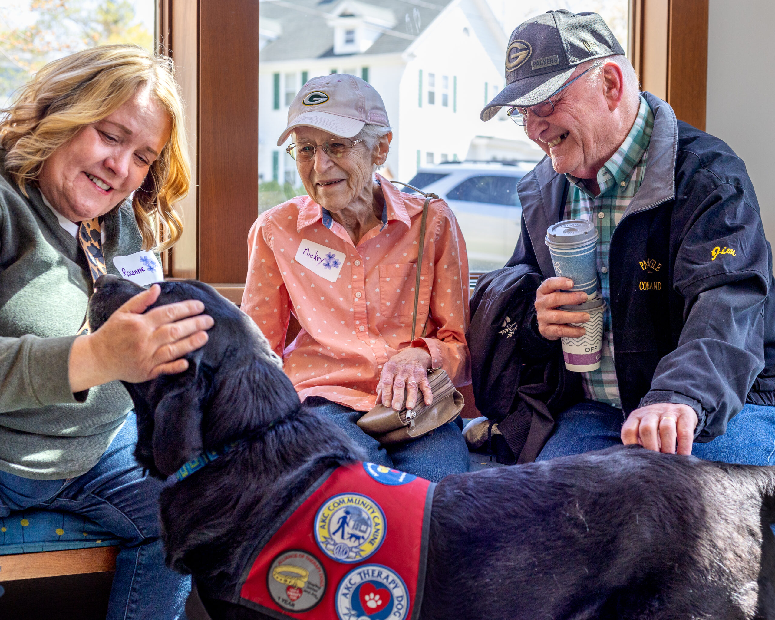 Two people look on as a dog handler pets her therapy dog