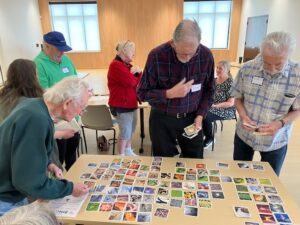 Older adults gathered around a table sorting cards with pictures on them.