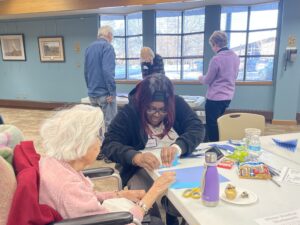 People working together at a table with crafting materials and snacks.