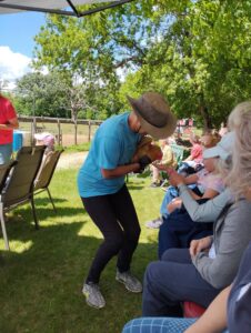Woman holds chicken so people sitting down can pet the chicken