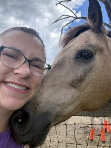 Woman with glasses leans in close to a horse for a hug