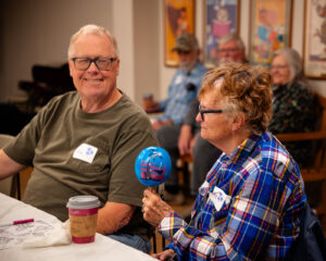 Woman holding a maraca, sitting next to a man smiling