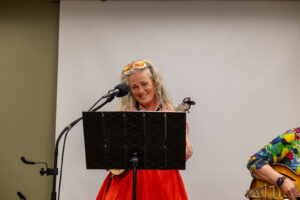 Musician playing a stringed instrument in front of a music stand, with a microphone in front of her.