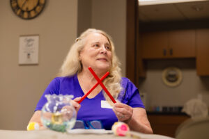 Woman holding rhythm sticks, crissed-crossed in front of her.