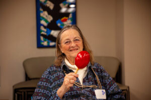 Woman holding a maraca while smiling slightly.