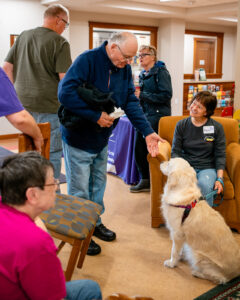 Man reaches his hand out to dog while others gather around in conversation