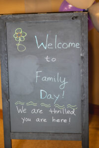 Chalk board easel with "Welcome to Family Day. We are thrilled you are here" in chalk writing