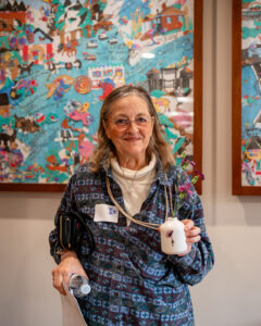 Woman holding a small bud vase with fresh flowers in it.