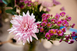 Close-up of a pink chrysanthemum and small magenta flowers with yellow centers.