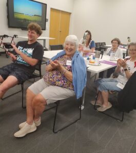 A group of people clapping and smiling in a classroom setting.