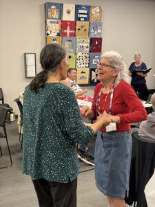Two women hold hands while dancing and smiling