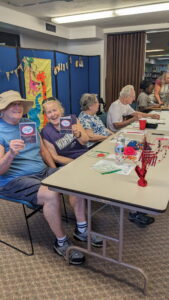 Participants seated at a table smiling and holding up hand crafted cards